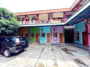 a car parked in front of a building with colorful doors at Harmony House Syariah near Alun Alun Pati Mitra RedDoorz in Pati