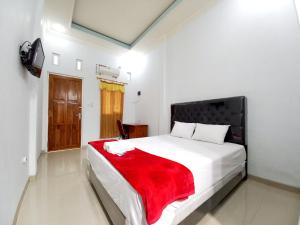 a bedroom with a bed with a red blanket on it at Harmony House Syariah near Alun Alun Pati Mitra RedDoorz in Pati