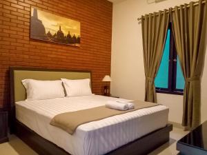 a bedroom with a bed and a brick wall at Omah Watu Homestay in Yogyakarta