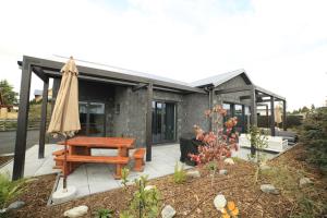 a house with a picnic table and an umbrella at Black Stilt Retreat, STUNNING luxury property in Twizel
