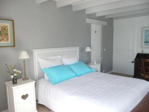 a bedroom with a white bed with blue pillows at Le Clos du Plantis in Sonnac