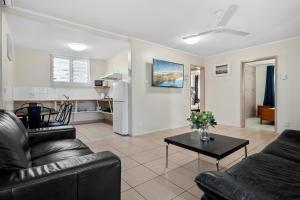 a living room with two leather couches and a table at Hotel Tropiq in Cairns