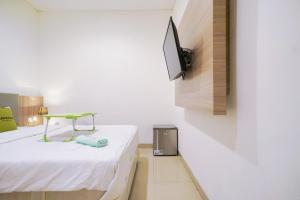 a room with a bed and a tv on a wall at Urbanview Hotel Bes Mangga Besar by RedDoorz in Jakarta