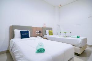 a hotel room with two beds with towels on them at Urbanview Hotel Bes Mangga Besar by RedDoorz in Jakarta