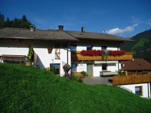 a white house with a balcony with flowers on it at Stübilerhof in San Giovanni in Val Aurina