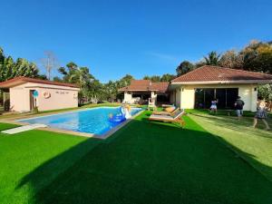 a backyard with a swimming pool and green grass at Sleep Soundly By The Sea in Ban Bang Pit Lang