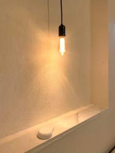 una luz colgando de una pared junto a un estante en Habitaciones Sancris, en San Cristóbal de Las Casas