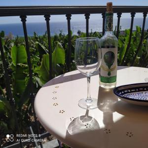 Trebol Trail Mountain La Palma Junto a Caracol في تازاكورتي: زجاجة من النبيذ وكأس من النبيذ على الطاولة