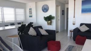 uma sala de estar com um sofá preto e uma mesa em #24 K I G Heights, Kings Beach - Stunning Views em Caloundra