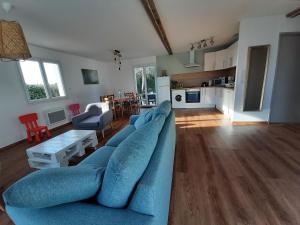 sala de estar con sofá azul y cocina en Gîte en pleine nature, A la douceur des Chênes, en Maubec