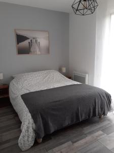 1 cama en un dormitorio blanco con una foto en la pared en Gîte en pleine nature, A la douceur des Chênes, en Maubec