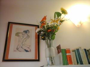 un vaso con fiori su uno scaffale vicino ai libri di Acero Rosso B&B apartment a San Lazzaro di Savena