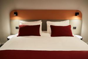 Atlas Aparthotel في بياترا نيامت: سرير كبير عليه وسادتين حمراء