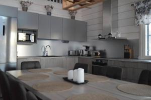 a kitchen with a table with chairs and a kitchen with white cabinets at Villa Vasa - new luxury villa next to lake in Meltaus