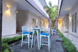 un patio con tavoli bianchi e sedie blu di Gaing Mas Residence By Gaing Mas Group a Jimbaran