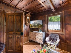 a living room with wooden walls and a window and a chair at Oberholzer Landhaus & Appartement in Ellmau