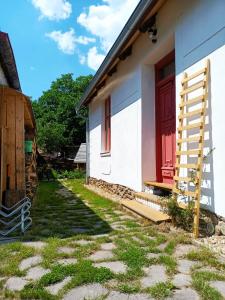 una casa blanca con una puerta roja y una escalera en Penzion Domek, en Dírná