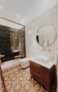 een badkamer met een wastafel, een toilet en een spiegel bij Kale Kapi City Living in Chania