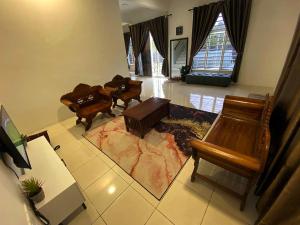 sala de estar con muebles de madera y alfombra en De Nadia Homestay, en Port Dickson