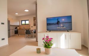 salon z telewizorem z płaskim ekranem na białej szafce w obiekcie Luxury apartment Grotta with sea view and swimming pool w mieście Premantura