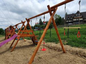 un parque infantil con columpios de madera en un campo en DOMKI SZMARAGD - Zniżki na Termy - Sauna - Bilard - Stoki Narciarskie -Śniadania, en Bukowina Tatrzańska