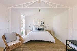 a white bedroom with a bed and a chair at Dovestones by the Sea Inverloch in Inverloch