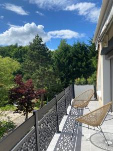 a balcony with two chairs and a fence and trees at Villa Manoca in Boisemont