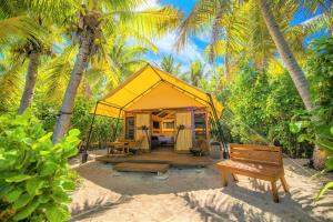 une tente jaune avec un banc et des palmiers dans l'établissement Barefoot Manta Island Resort, à Drawaqa Island