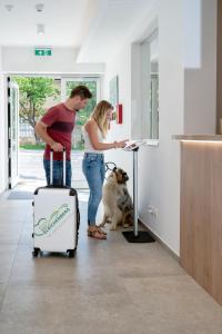 a man and a woman with a suitcase and a dog at Landhaus Bad Gleichenberg in Bad Gleichenberg