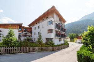 een wit gebouw met een houten hek naast een straat bij Alpenleben in Sankt Anton am Arlberg