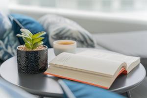 stół z książką, filiżanką kawy i rośliną w obiekcie Apartament Sapphire Rogowo Pearl w mieście Mrzeżyno
