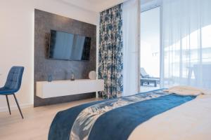 a bedroom with a bed and a tv on a wall at Apartament Sapphire Rogowo Pearl in Mrzeżyno