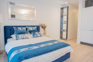 a blue and white bed in a white bedroom at Apartament Sapphire Rogowo Pearl in Mrzeżyno