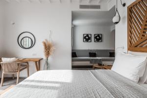 a white bedroom with a bed and a couch at Alissachni Mykonos in Psarou