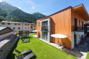 a patio with chairs and umbrellas on a building at Anthony's Peaks & Pillows in Sankt Anton am Arlberg