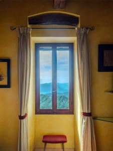 una ventana con cortinas y un taburete rojo en una habitación en Fattorie di Montechiaro, en Sasso Marconi