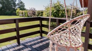 a swinging chair on a porch with a field at Sasinowe Zacisze in Sasino