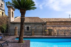 a palm tree next to a house with a swimming pool at Hotel Villa Carlotta in Taormina