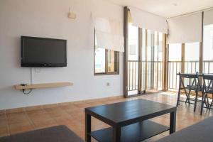 a living room with a table and a tv on a wall at Las Minvas Relax in Grao de Castellón