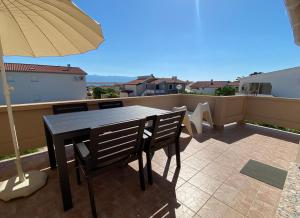 a table and chairs on a balcony with an umbrella at Beachfront Apartment in Vir