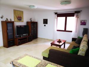 sala de estar con sofá y TV de pantalla plana en Apartamento en primera línea de Playa Las Canteras, en Las Palmas de Gran Canaria