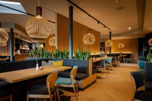 un restaurante con mesas, sillas y luces colgantes en eduCARE Hotel, en Treffen