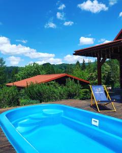 een blauw zwembad met een stoel naast een huis bij Dom Wakacyjny Letnisko in Ujsoły
