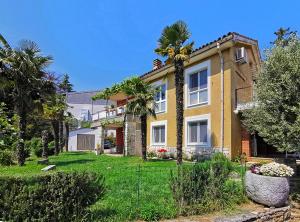 a yellow house with palm trees in a yard at Apartments Nea by Locap Group in Portorož