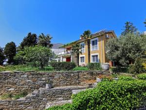 a large yellow house with a stone wall at Apartments Nea by Locap Group in Portorož