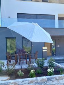 a table with a white umbrella in front of a building at Mosel-FeWo-JuLe in Enkirch