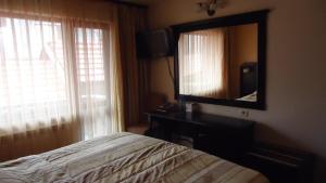 una camera da letto con un letto e un grande specchio di Family Hotel Shipkovo a Shipkovo Altre 38 foto