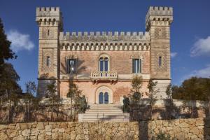 a building with a tower on top of a stone wall at Castle Elvira - The Castle & The Cottage in Trepuzzi