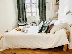 um quarto com uma cama com lençóis brancos e almofadas em L emeraude - Trouville em Trouville-sur-Mer