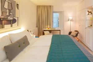 チューリッヒにあるホテル ロスリの大きなベッドとデスクが備わるホテルルームです。